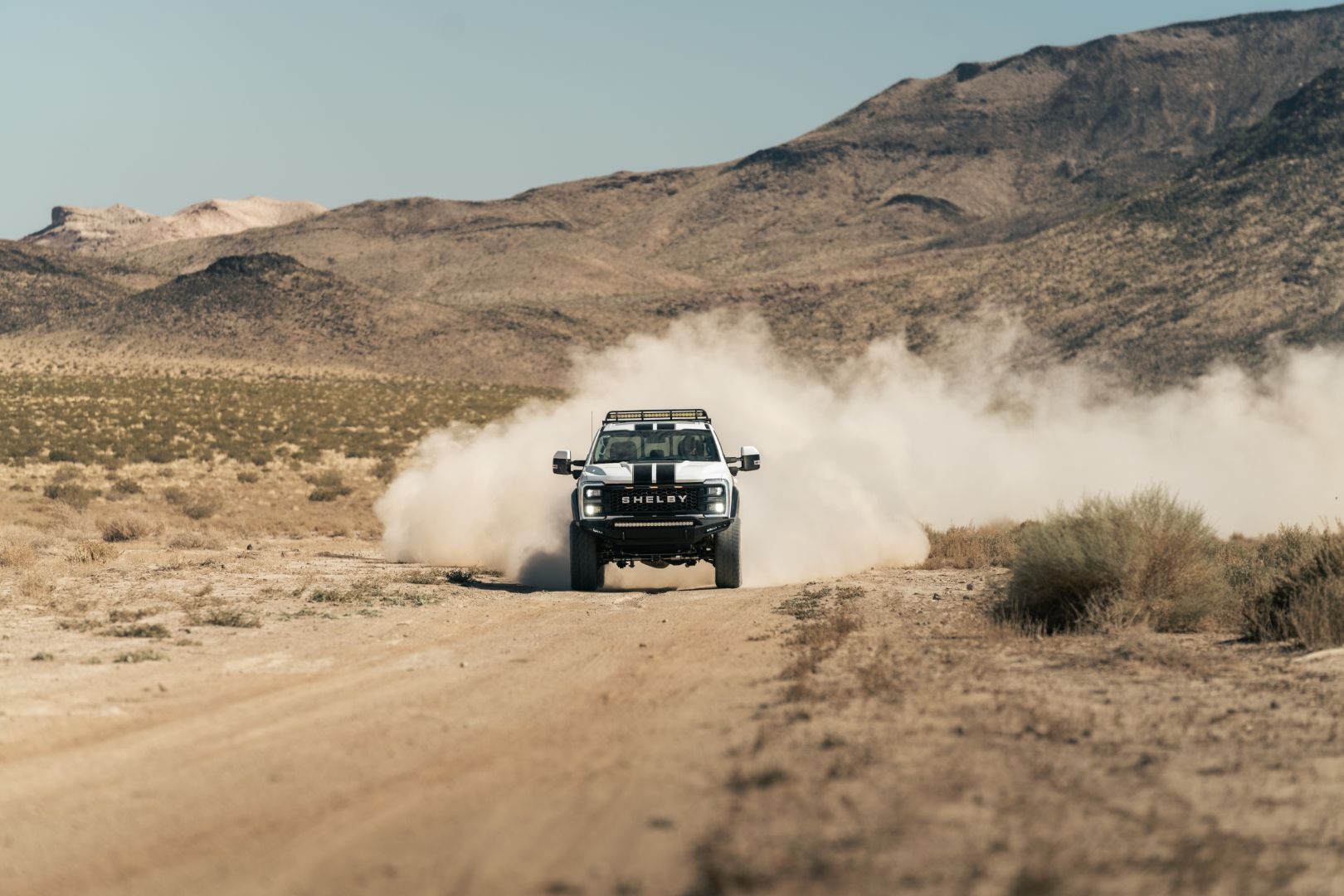 2024 Ford F-250 Shelby Super Baja driving through the desert, leaving a dust trail